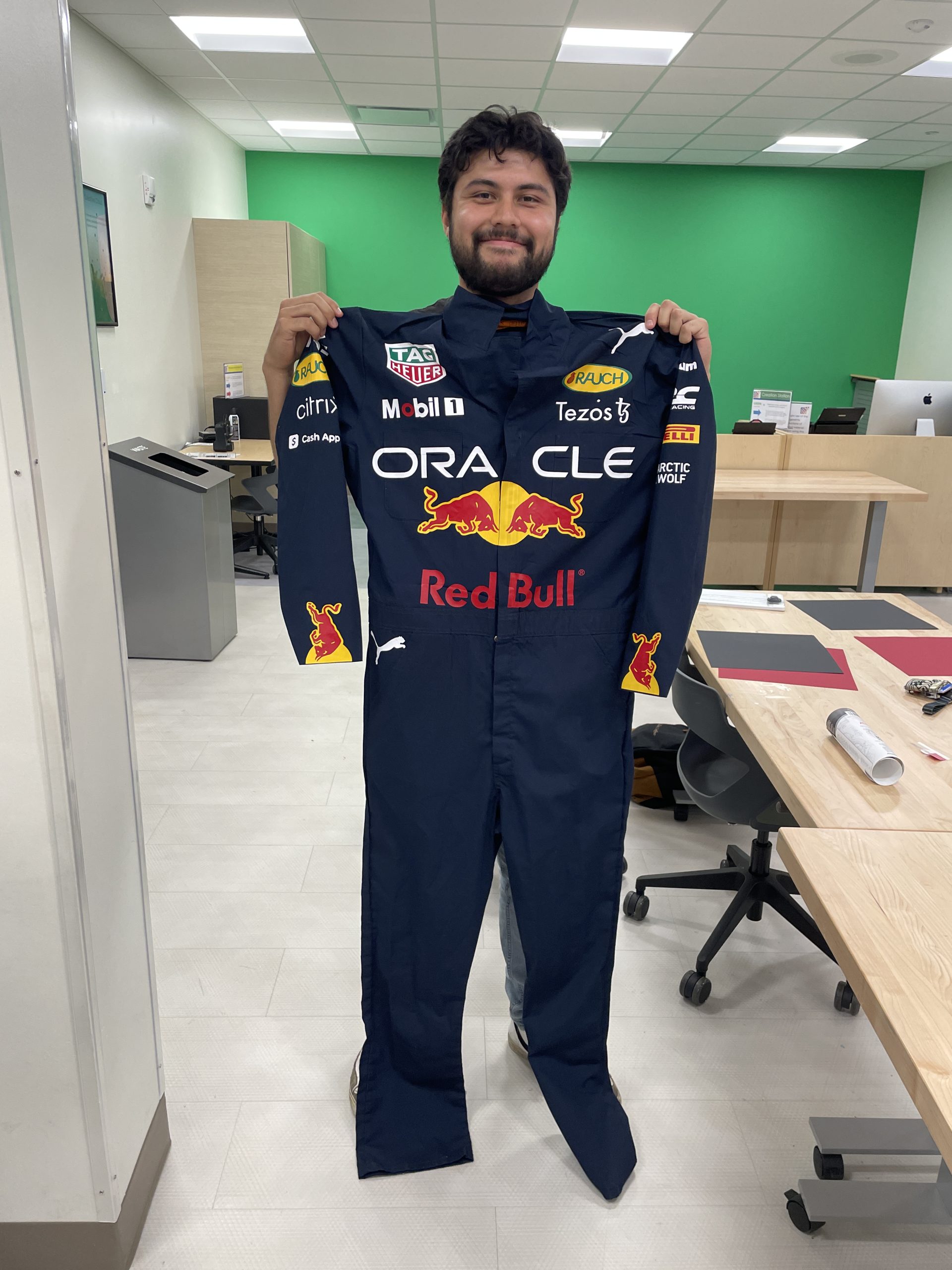 Man holding a costume of an F1 racing suit with Oracle and Redbull logos.
